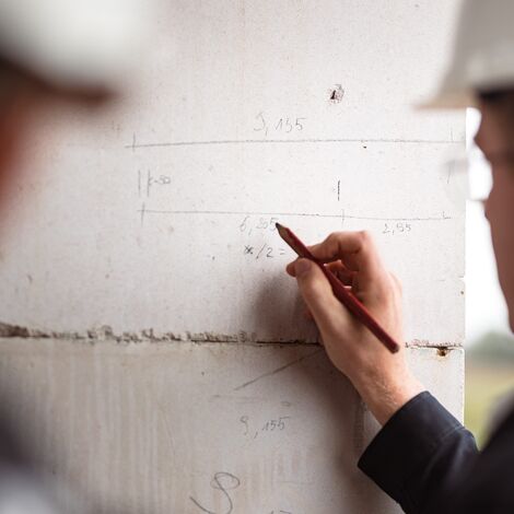 building professionals drawing measurements on concrete wall