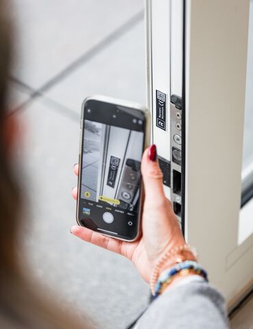 Тримайте смартфон біля QR-коду на білому віконному профілі.