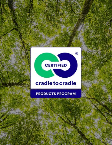 Логотип Cradle to Cradle на фоні зелених верхівок дерев.